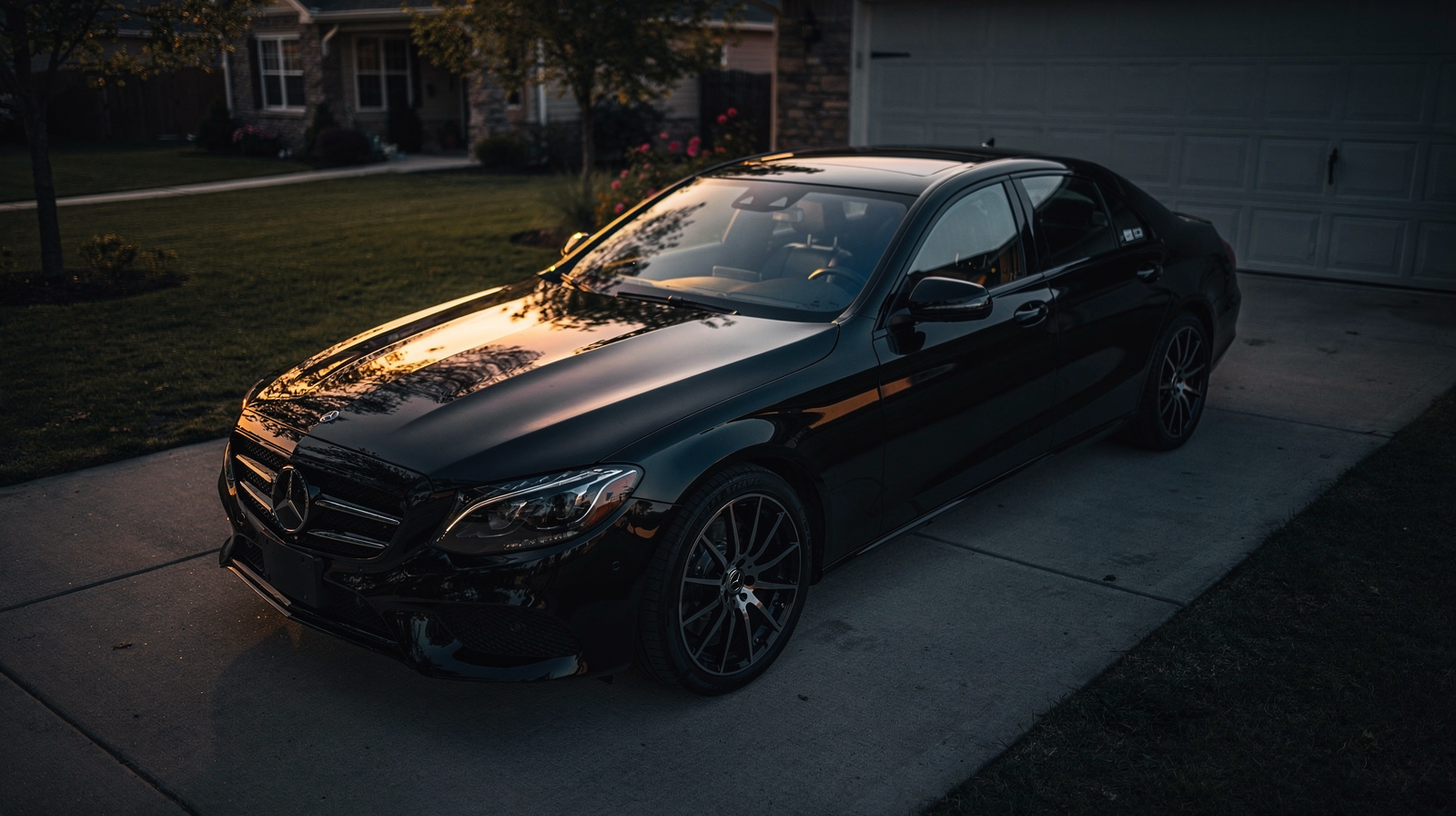 Mobile car detailing setup in a residential driveway at dawn with pressure washer, bucket, and detailing van visible in cinematic moody lighting