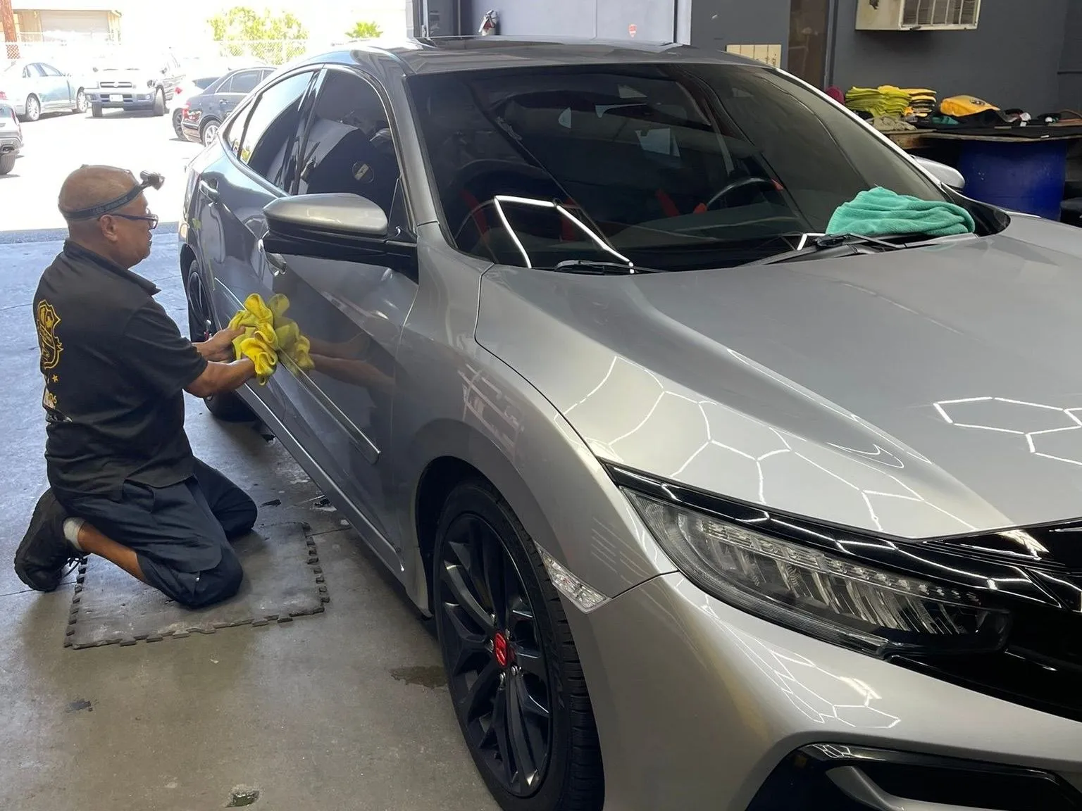 Hand finishing a Honda Civic Si inside the Chinto Auto Detailing shop